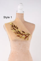 A mannequin with a beige dress and a decorative leaf design on the chest area.