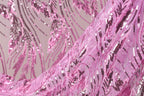 a close-up view of a fabric with a pink sequin pattern. The fabric appears to be made of a sheer material, with a delicate and intricate design featuring pink and purple sequins. The fabric is folded and draped, creating a visually appealing and textured appearance.