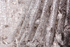 The image is a close-up of a fabric with a silver sequin pattern, featuring a delicate floral design.