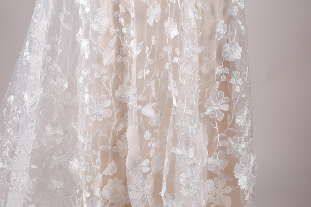 a close-up view of a delicate, white lace dress with a floral pattern.