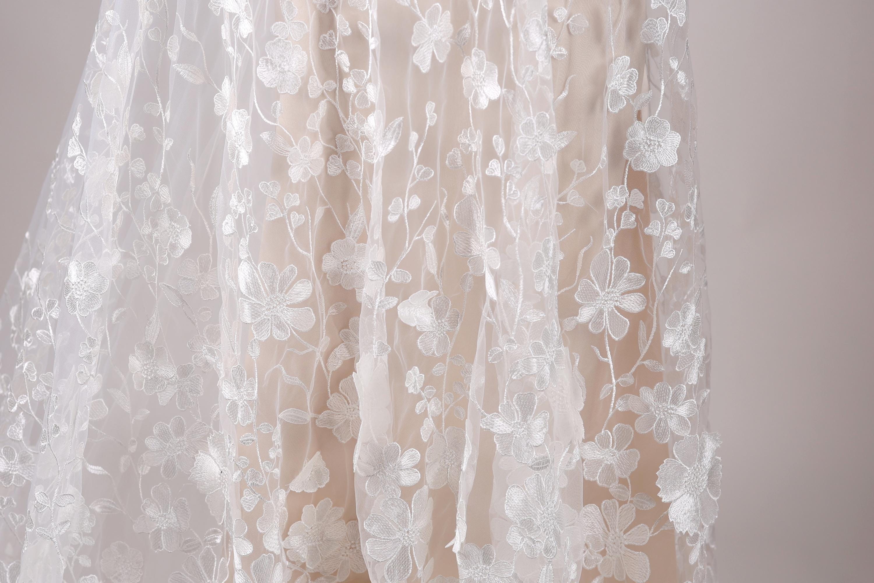 a close-up view of a delicate, white lace dress with a floral pattern.