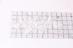 a transparent ruler with a grid pattern, placed on a white surface.