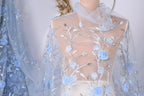 a mannequin wearing a sheer, blue-colored fabric with delicate floral embroidery. The fabric has a light blue color and appears to be made of sheer material, giving it a delicate and airy appearance.