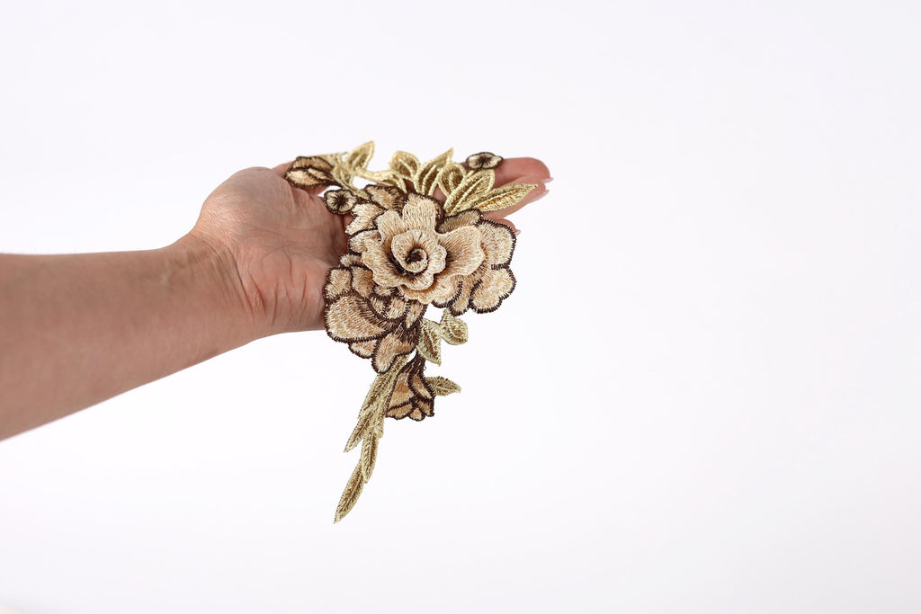 A hand holding a delicate flower embroidered on the palm against a plain white background.