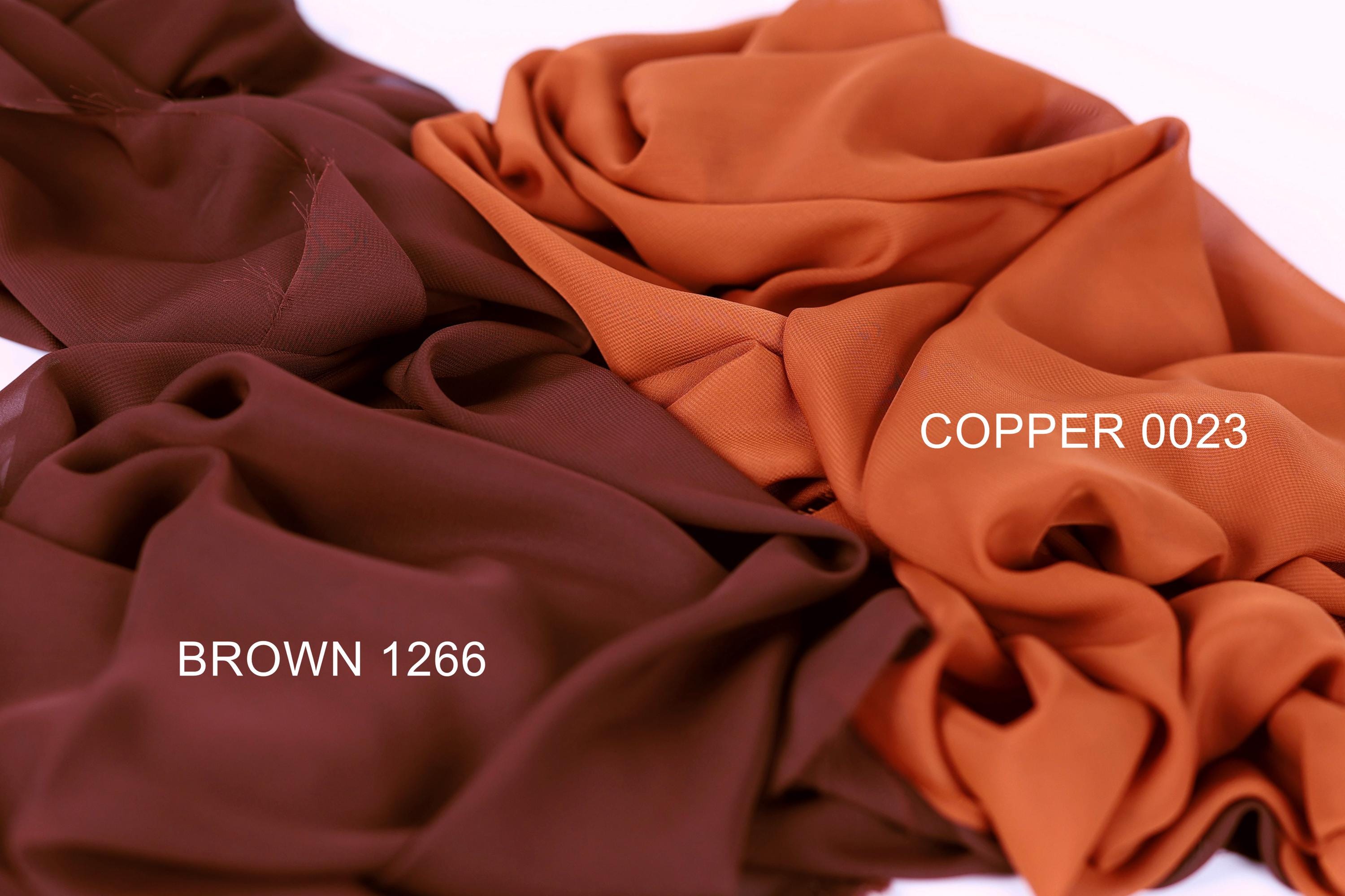 three different fabric swatches, each with a distinct color: brown, copper, and brown. The swatches are arranged in a way that allows for easy comparison and identification of the colors.