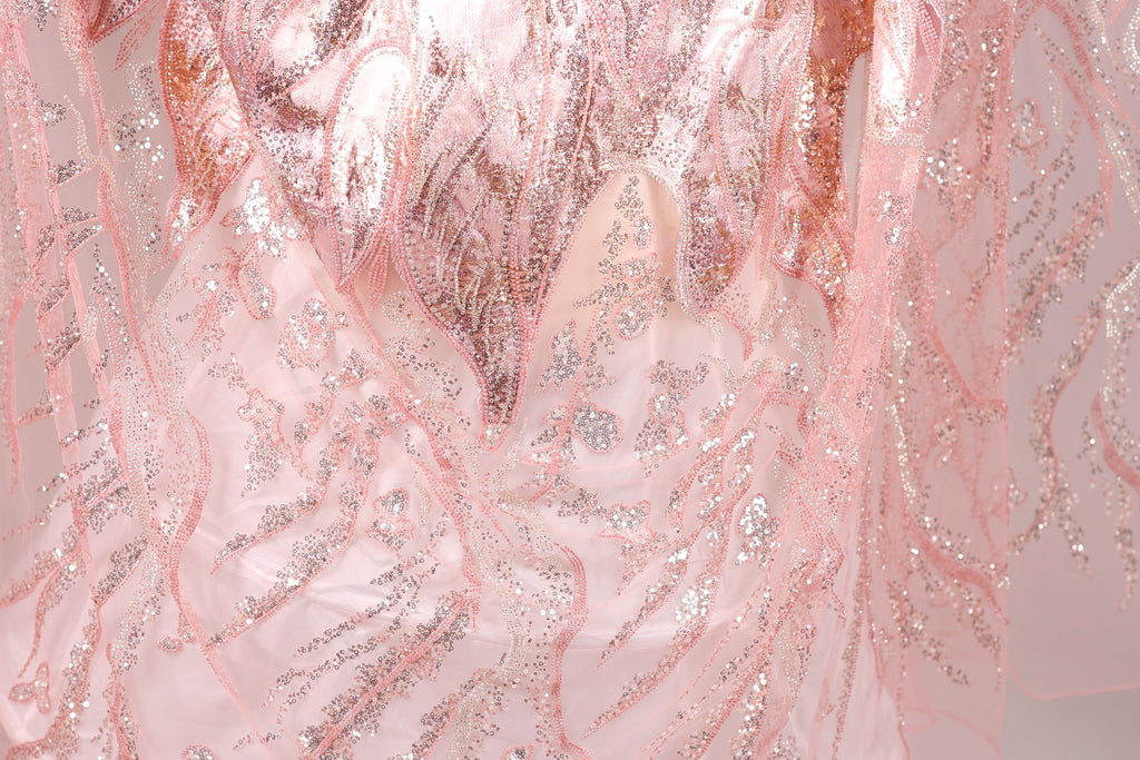 The image is a close-up of a fabric with a pink and silver pattern, featuring a delicate and intricate design.