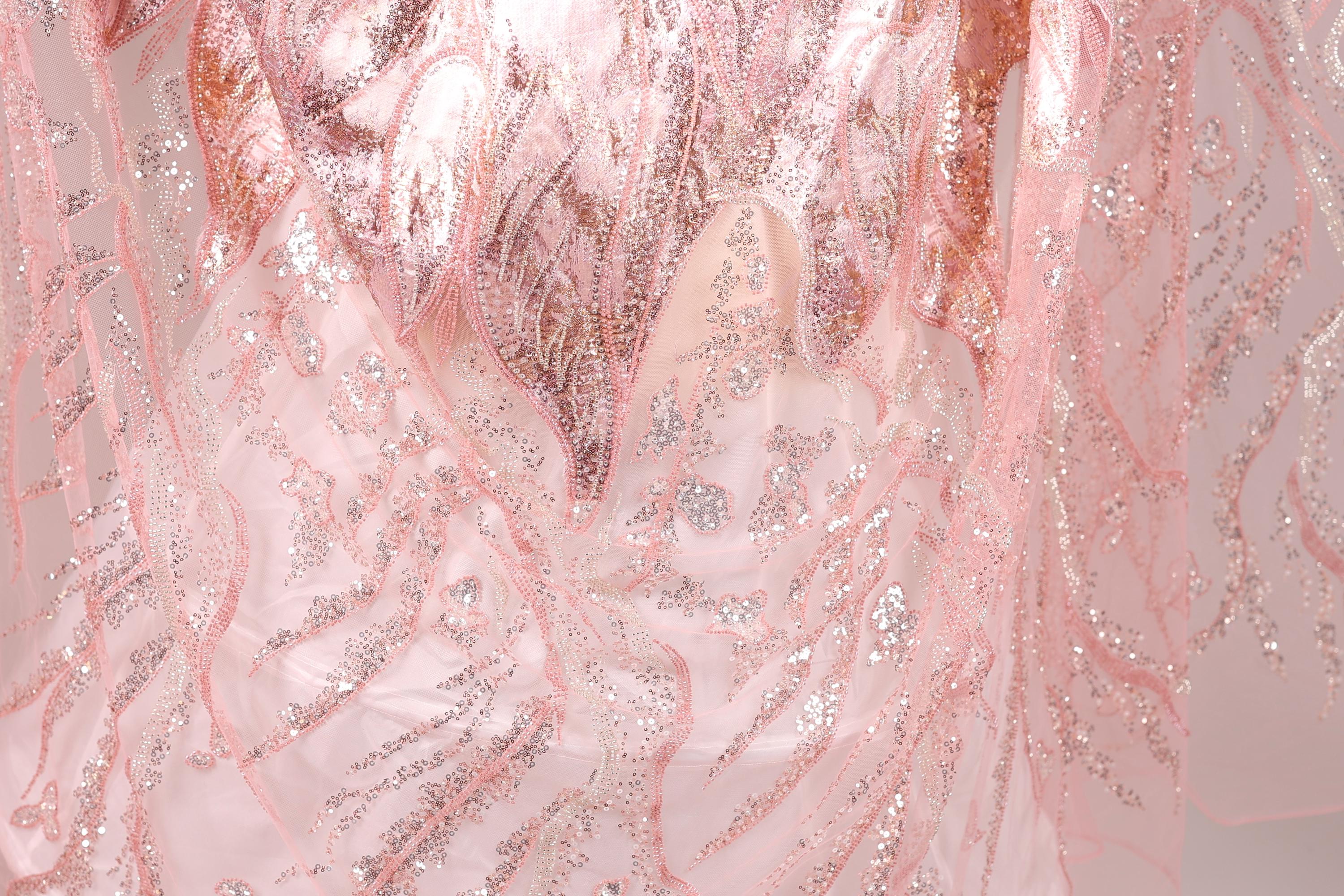 The image is a close-up of a fabric with a pink and silver pattern, featuring a delicate and intricate design.
