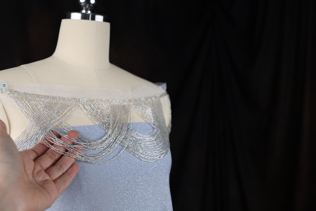 a woman is holding a beaded dress on a mannequin