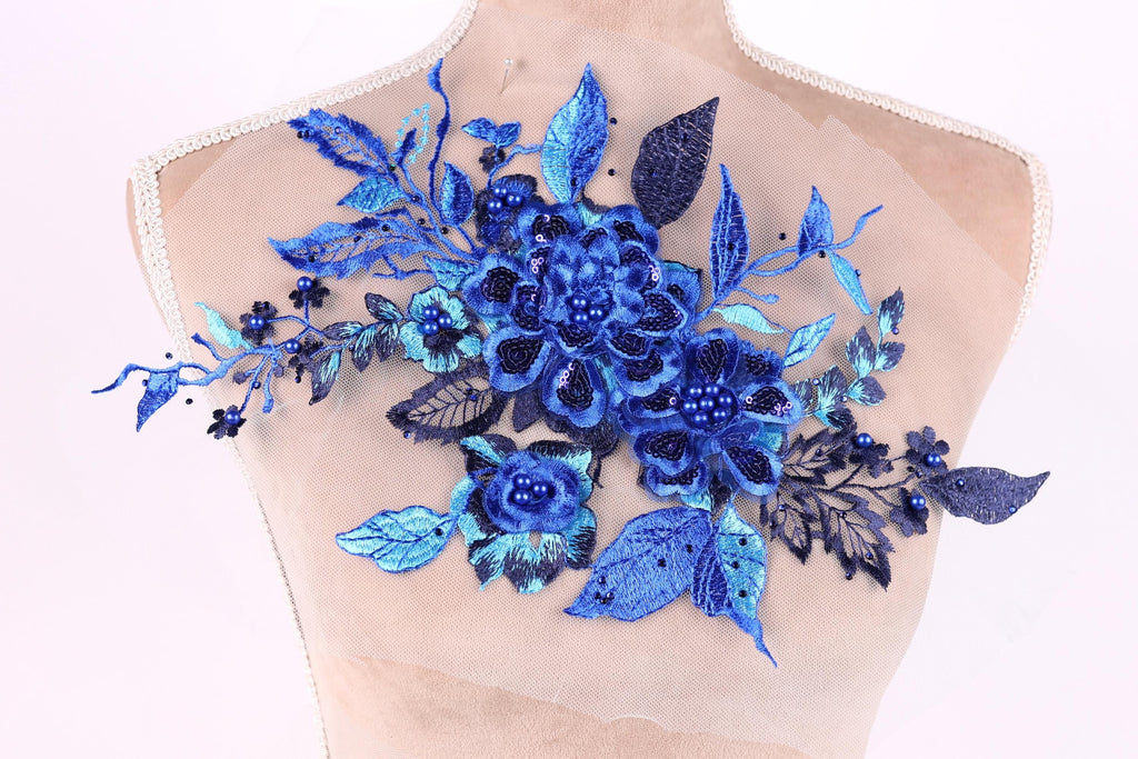 A mannequin torso with a decorative blue floral embroidery on it.