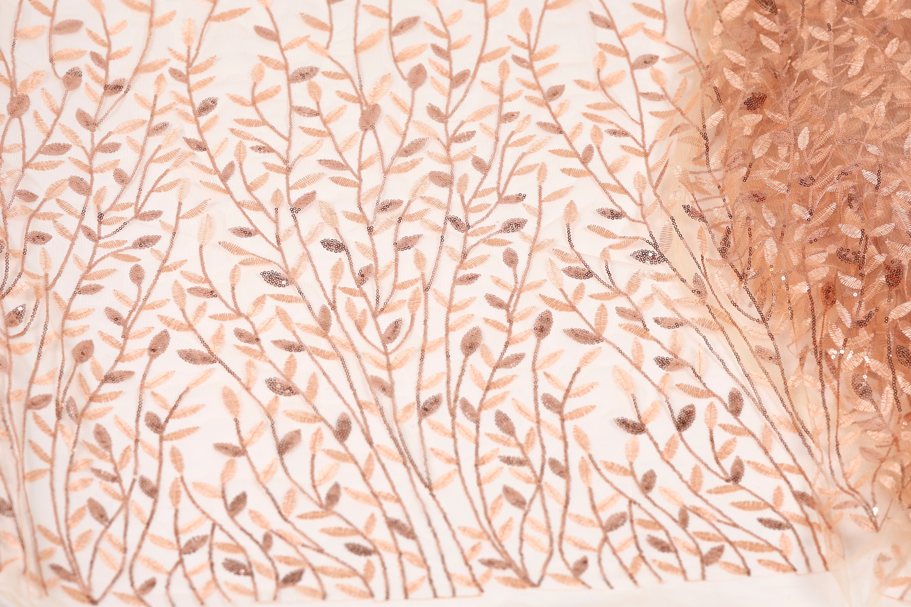 a close-up view of a fabric with a repeating pattern of brown and beige leaves and branches, creating a textured and visually appealing design.