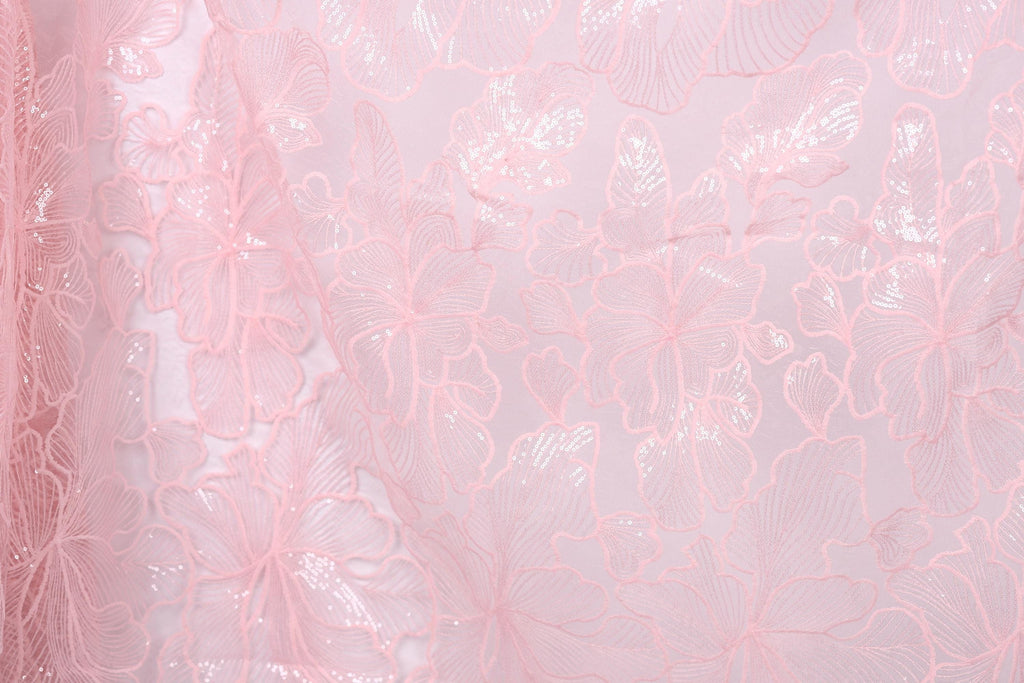 a close-up view of a delicate, pink, lace-like fabric with a floral pattern. The fabric appears to be made of sheer material, giving it a soft and delicate appearance. The floral pattern consists of various shades of pink, ranging from light to dark, creating a visually appealing and intricate design. The fabric is spread across the entire image, filling the frame and drawing the viewer's attention to its delicate texture and intricate design.