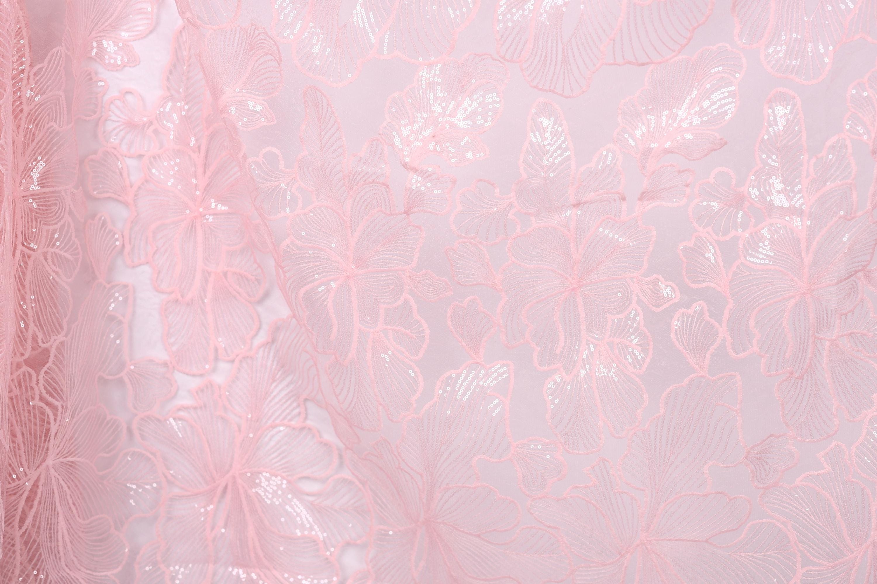 a close-up view of a delicate, pink, lace-like fabric with a floral pattern. The fabric appears to be made of sheer material, giving it a soft and delicate appearance. The floral pattern consists of various shades of pink, ranging from light to dark, creating a visually appealing and intricate design. The fabric is spread across the entire image, filling the frame and drawing the viewer's attention to its delicate texture and intricate design.
