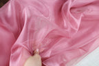 a person is stitching a piece of pink fabric