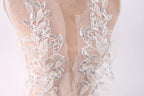 a close-up view of a delicate, lace-like fabric with intricate floral patterns. The fabric appears to be a sheer material, possibly a wedding dress or a bridal gown, with a lace bodice and a sheer overlay. The lace patterns are visible on the back of the fabric, creating a visually appealing and elegant design.