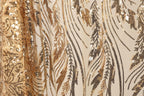 a close-up view of a fabric with a gold and black sequin pattern. The fabric appears to be a sheer material, with a repeating pattern of sequins and leaves. The pattern is intricate and detailed, with the sequins and leaves creating a visually striking design.