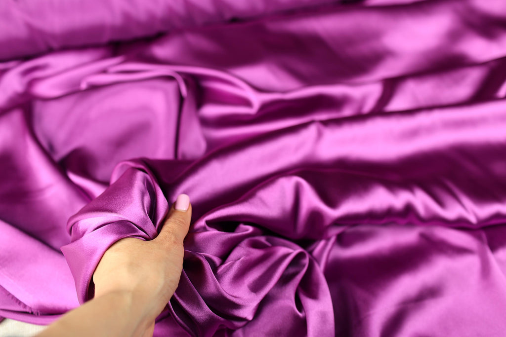 a person is holding a piece of purple fabric