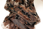a close-up view of a fabric with a floral pattern, featuring a mix of brown, black, and gold colors. The fabric appears to be made of a sheer material, giving it a delicate and intricate appearance.