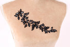 a close-up view of a mannequin torso with a decorative black leaf embroidered on it.