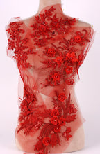 a mannequin with a red, sheer fabric dress adorned with intricate floral and leaf designs. The dress appears to be made of tulle and has a delicate, elegant appearance.