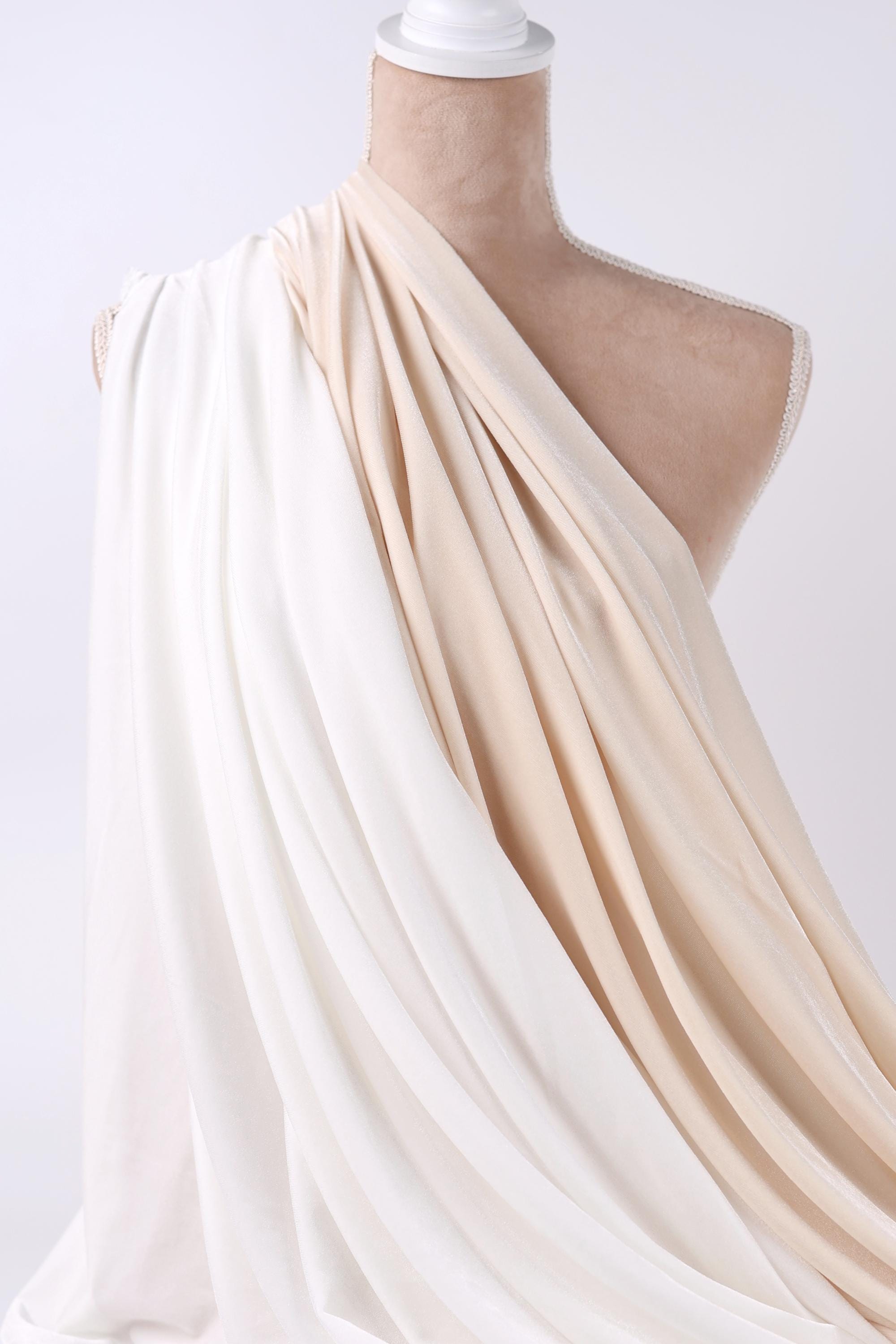 A mannequin wearing a white and beige draped fabric draped over its torso.