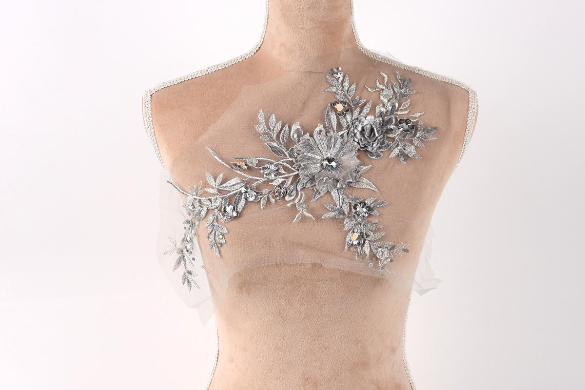 A mannequin with a decorative silver floral embellishment on its bust.