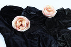 two pink roses resting on a black velvet background.
