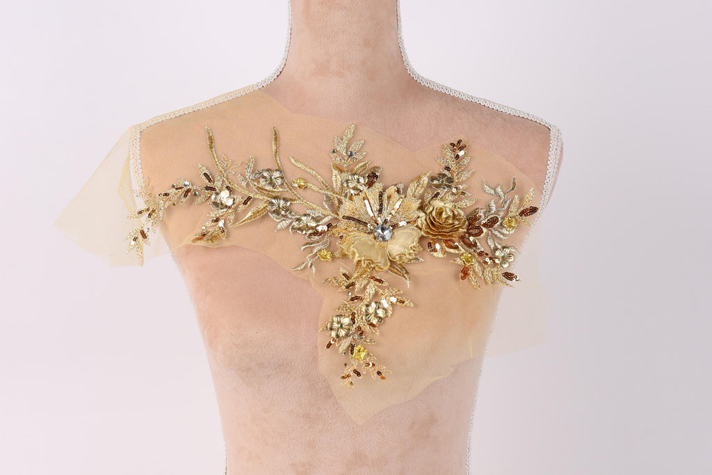 A mannequin wearing a beige dress with a decorative floral embroidery on the shoulder area.