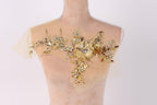 A mannequin wearing a beige dress with a decorative floral embroidery on the shoulder area.