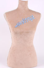 A mannequin with a beige body and a blue floral embroidered on its chest.