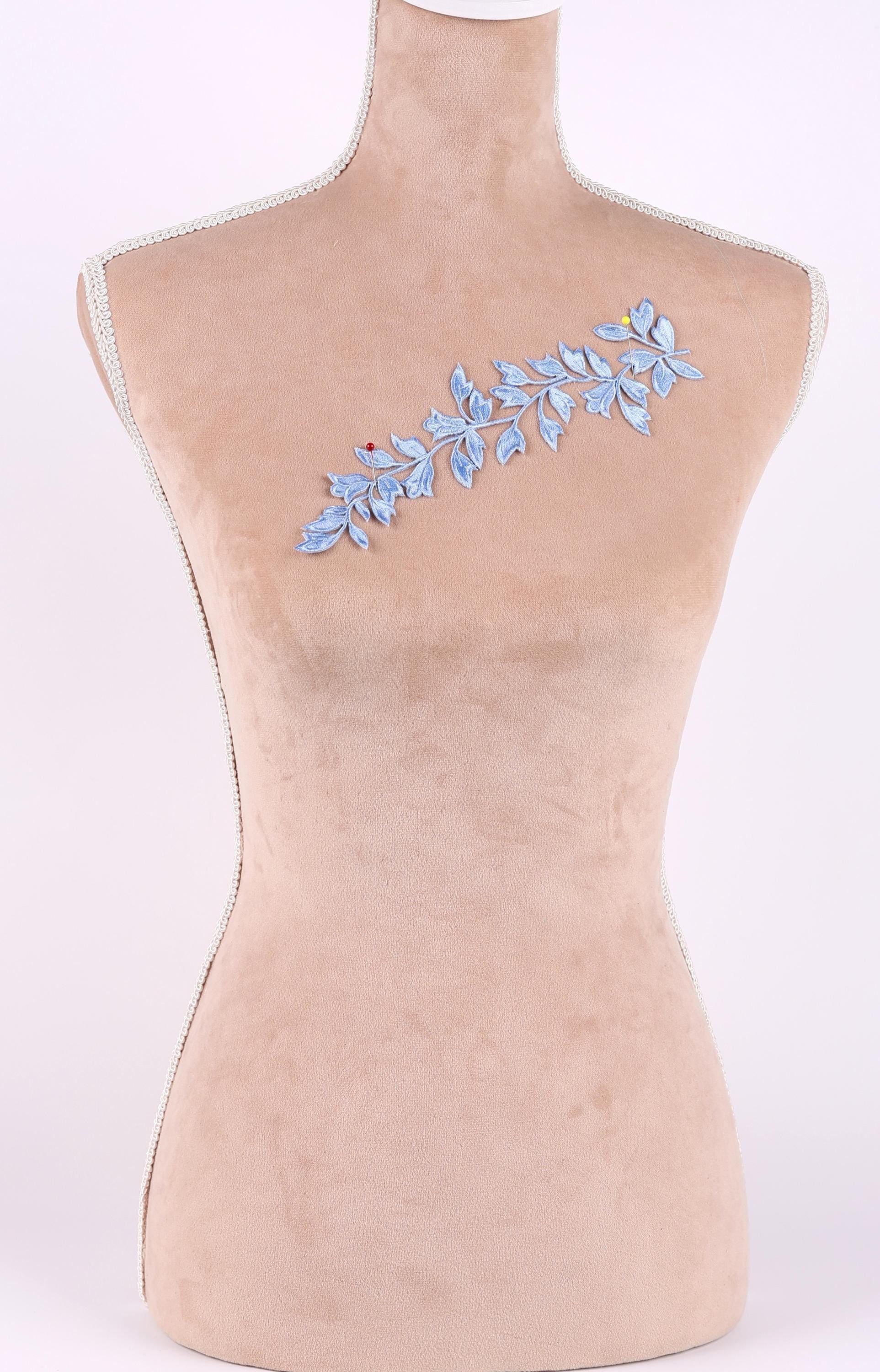A mannequin with a beige body and a blue floral embroidered on its chest.