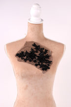A mannequin head with a black lace or sequin embellishment on the chest area.