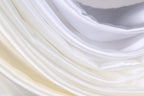 The image is a close-up of a soft, flowing fabric with a gradient of white and yellow colors. The fabric appears to be made of silk or satin, and it has a smooth, shiny texture. The colors are vibrant and the fabric is draped in a way that creates a sense of movement and softness.