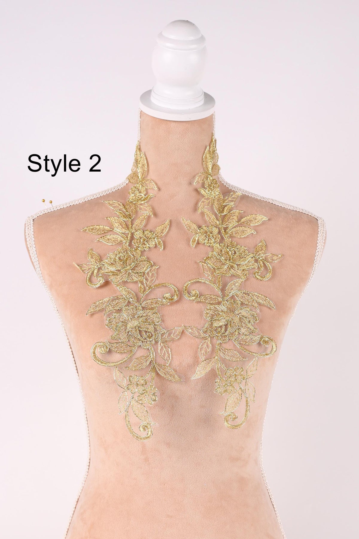 A mannequin wearing a gold-colored lace collar with intricate floral designs.