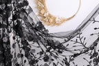 a black lace fabric with a floral pattern, and a wreath made of dried flowers and branches.