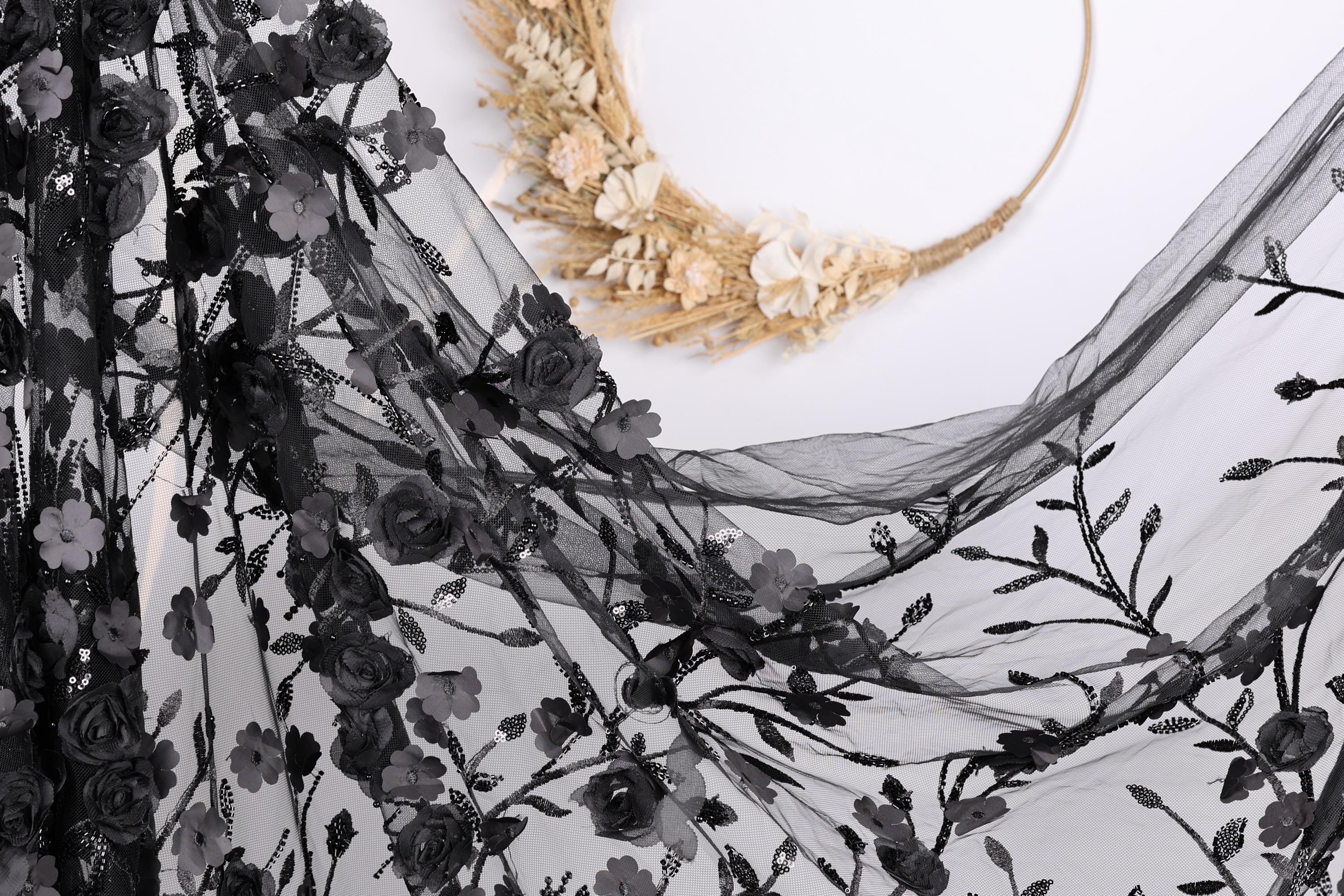 a black lace fabric with a floral pattern, and a wreath made of dried flowers and branches.