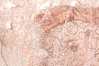 A close-up view of a hand holding a delicate, intricately embroidered fabric with a floral pattern.