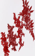 a close-up view of red embroidered or crocheted fabric with intricate floral and leaf patterns.