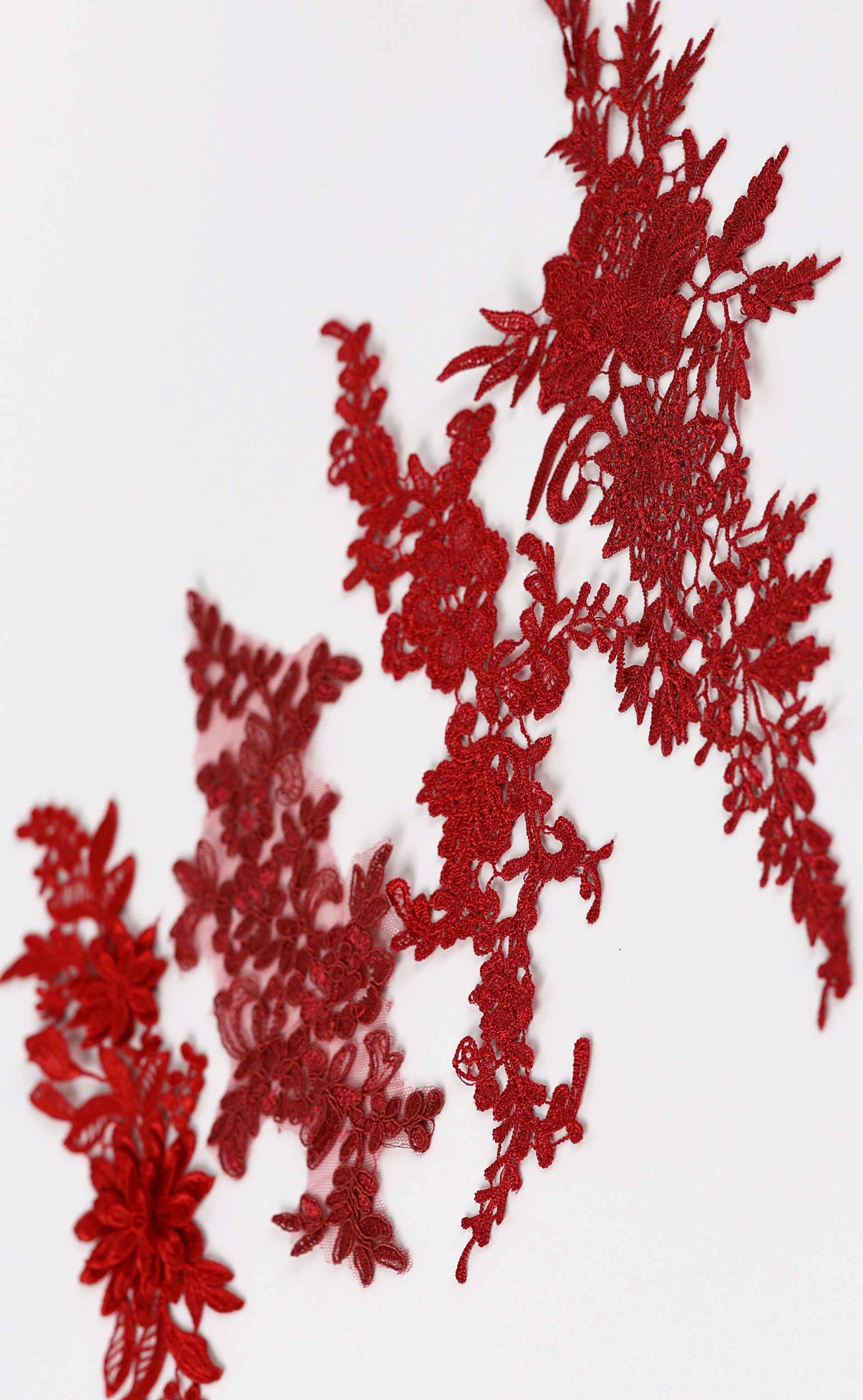 a close-up view of red embroidered or crocheted fabric with intricate floral and leaf patterns.