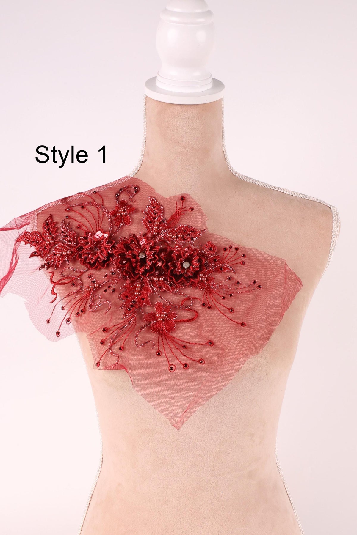 A mannequin wearing a red floral embellishment on its shoulder.