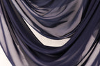 a close-up view of a fabric with a dark blue color, possibly a chiffon or a similar type of material. The fabric appears to be folded or draped in a way that creates a sense of depth and texture.