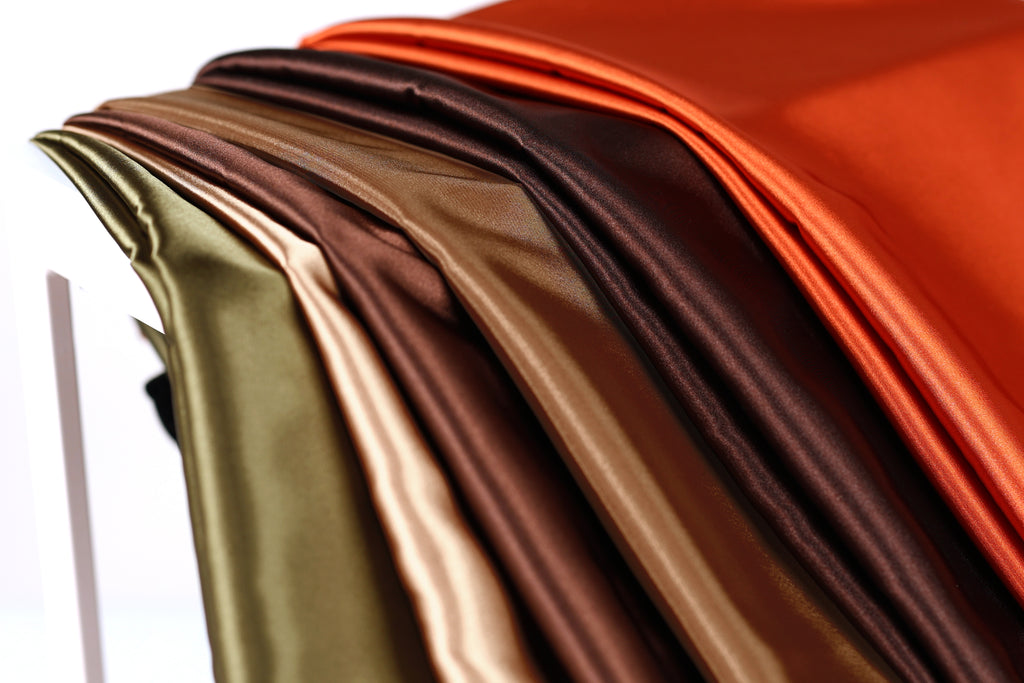 A close-up view of a collection of colorful fabric swatches, including shades of green, brown, orange, and red.