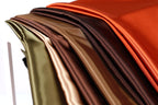 A close-up view of a collection of colorful fabric swatches, including shades of green, brown, orange, and red.