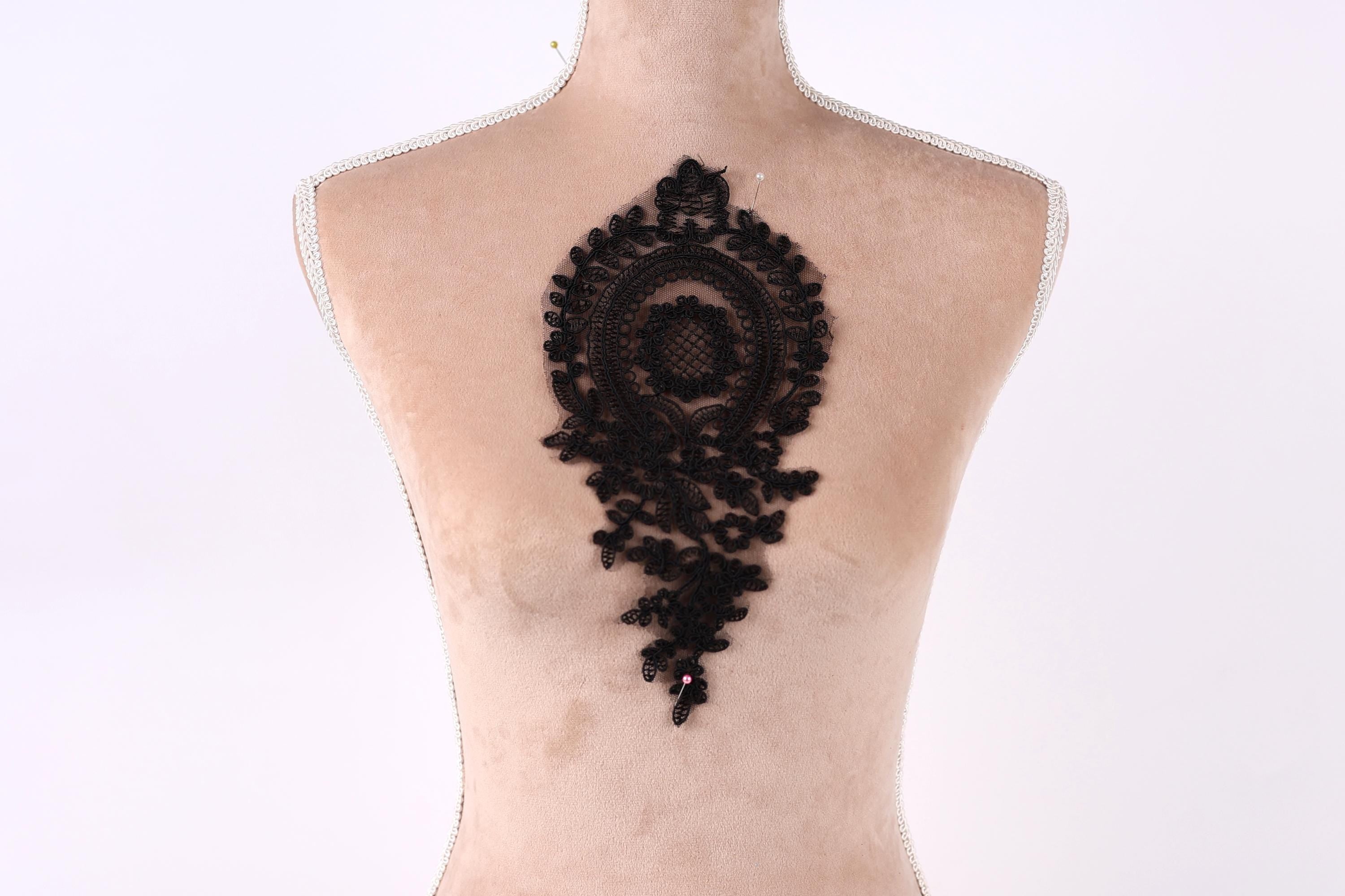 a mannequin with a black lace design on its back.