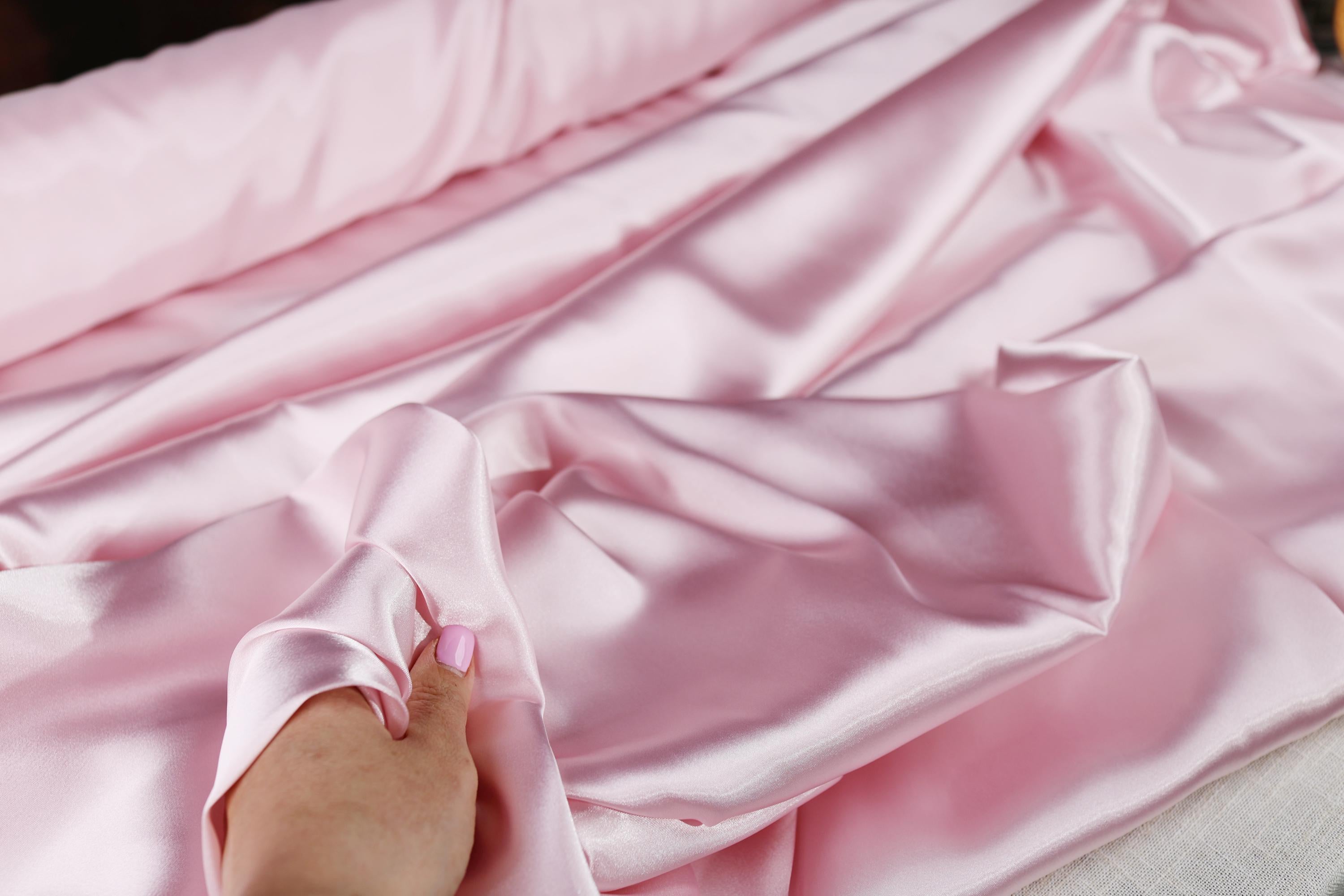 a person&#39;s hand on a pink satin material