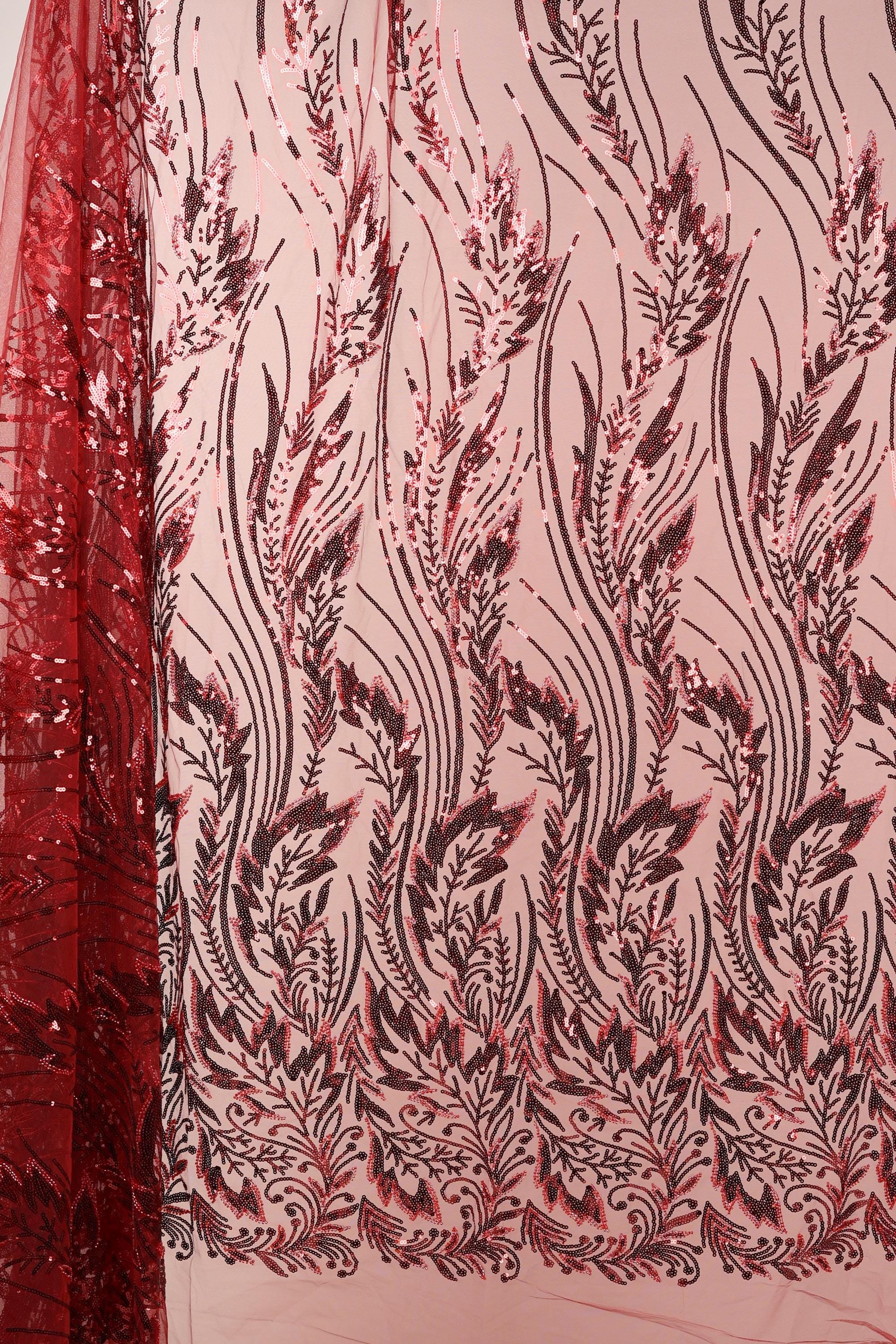 a close-up view of a fabric with a floral pattern in shades of red and black. The pattern consists of various leaf-like shapes and lines, creating a visually striking and intricate design. The fabric appears to be made of a material with a shimmering or sequined texture, adding a touch of elegance and sophistication to the overall appearance.