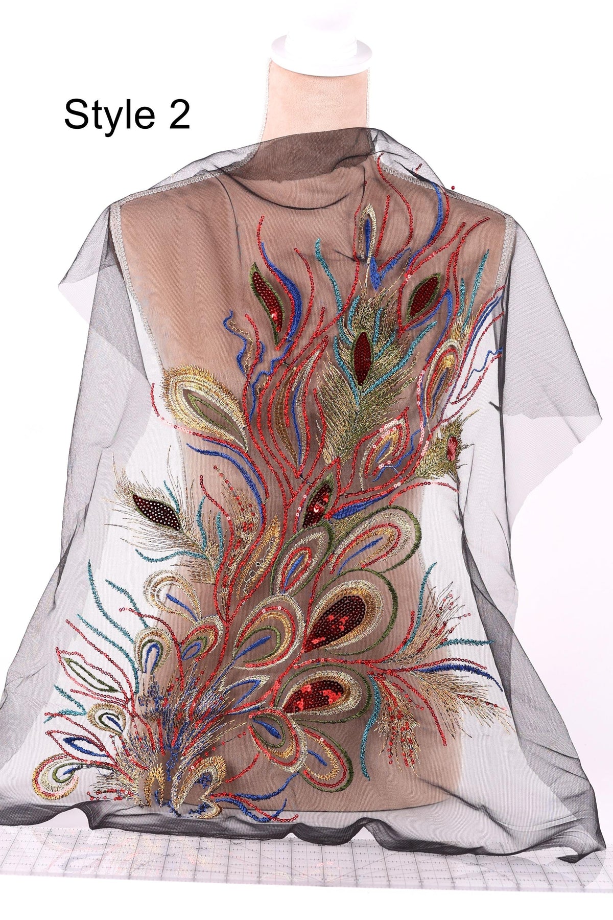 A mannequin wearing a decorative, colorful, and intricate dress with a sheer, sheer-like fabric overlay.