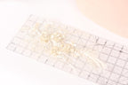 a clear ruler with a delicate floral design on it, placed on a white surface.