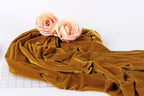 two pink roses resting on a crumpled, golden fabric, which appears to be a piece of velvet or a similar material.