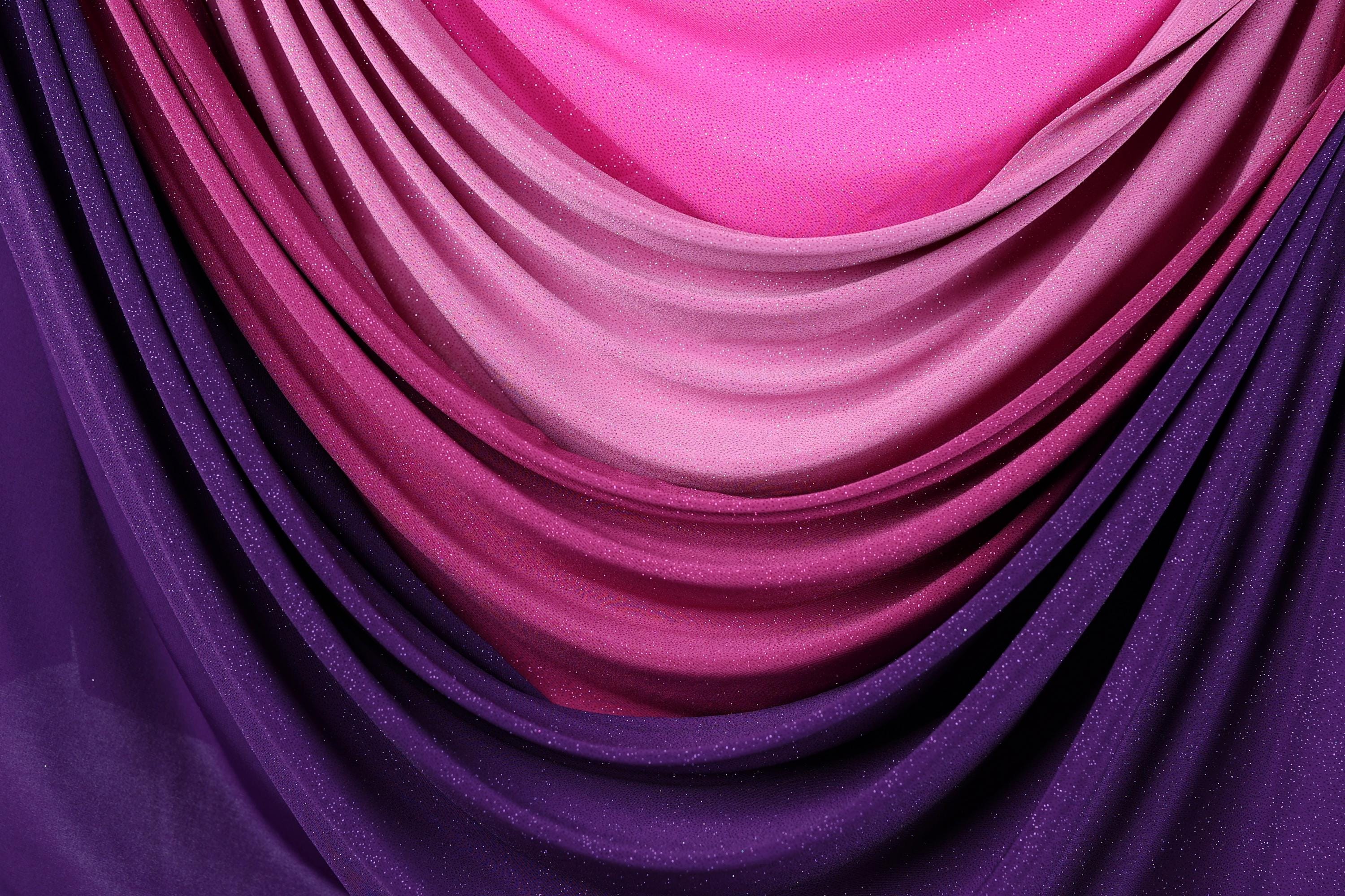 a close-up view of a fabric with a gradient of colors, transitioning from purple to pink. The fabric appears to be made of a shiny, glittery material, adding a touch of sparkle to the overall appearance.