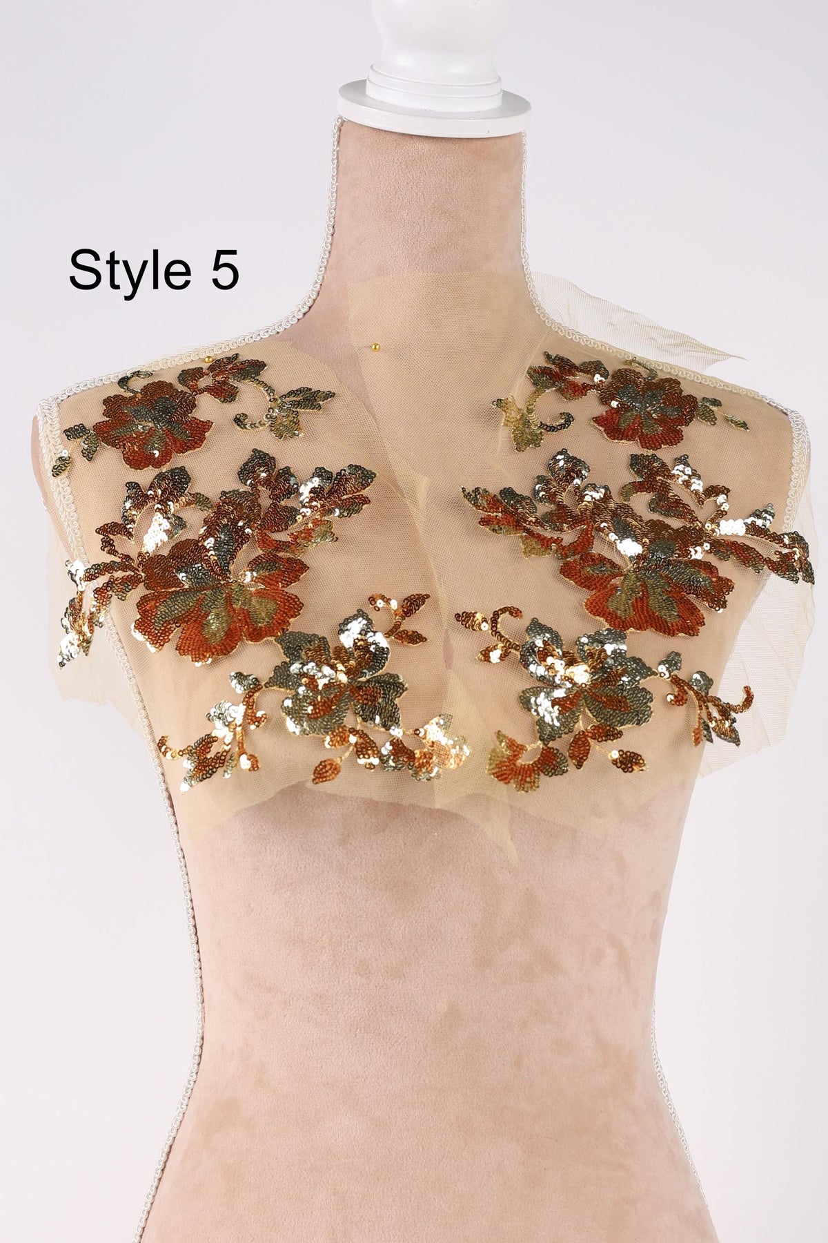 A mannequin wearing a beige dress with a floral pattern of red and green sequins.